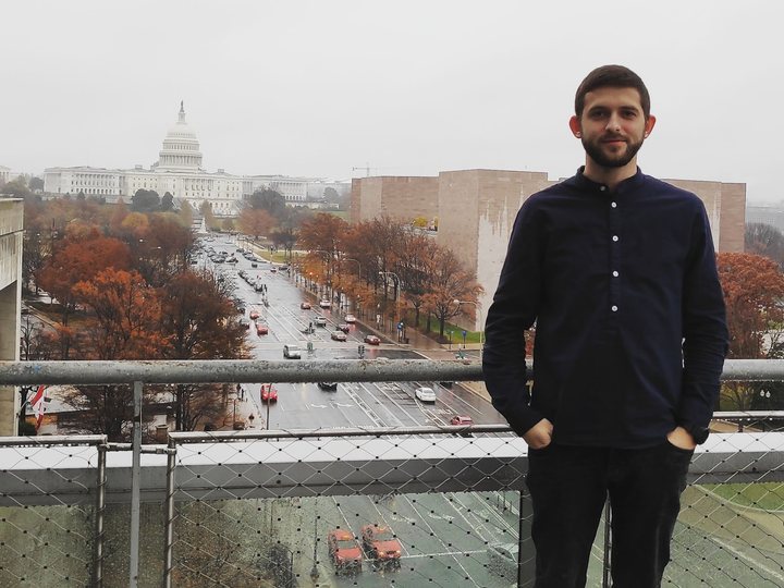 Alex on a rooftop in Washington, D.C., with the Capitol behind him